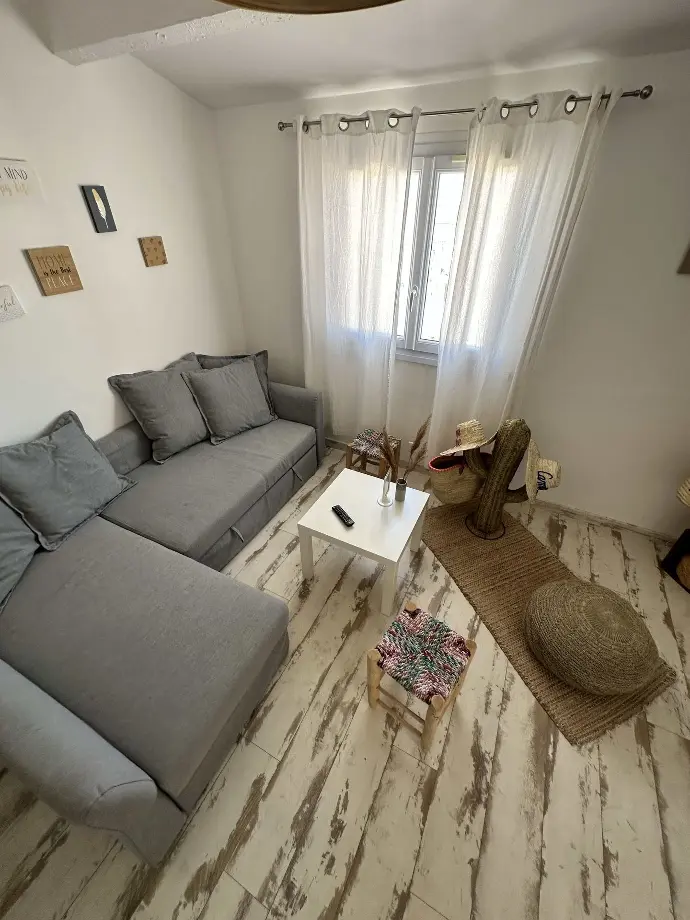 Salon confortable de l’appartement de vacances Loc’Amargue avec un canapé gris, une table basse blanche et des œuvres d’art murales