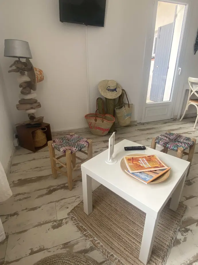 Salon accueillant de Loc'Amargue avec table basse, chaises colorées, lampe rustique et accessoires de plage aux Saintes-Maries-de-la-Mer