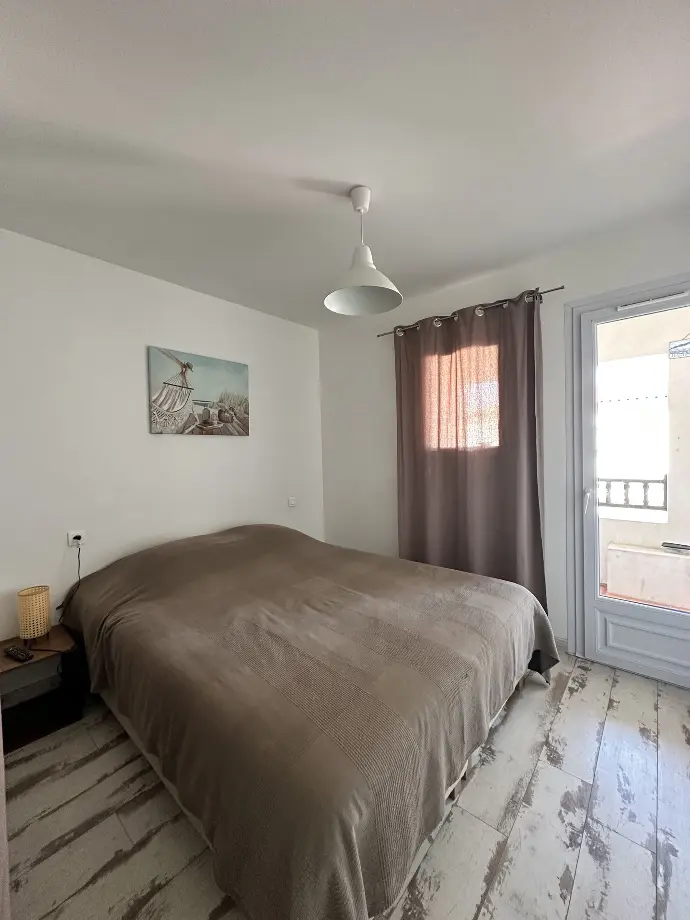 Chambre à coucher sereine avec grand lit, couverture marron, œuvre d'art maritime et rideaux assortis à Loc'Amargue