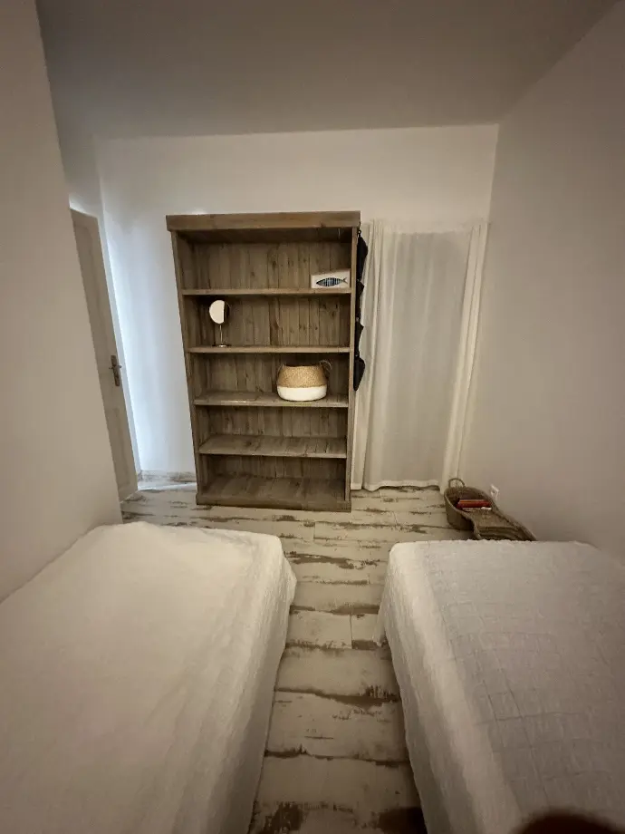 Chambre douillette avec deux lits simples, étagère en bois et décoration nautique à Loc'Amargue aux Saintes-Maries-de-la-Mer