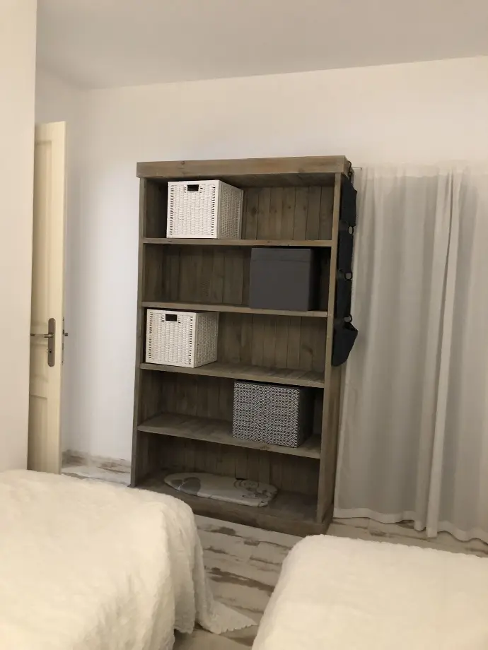 Chambre partagée avec deux lits simples, étagère en bois avec paniers de rangement et rideaux blancs à Loc'Amargue, Saintes-Maries-de-la-Mer