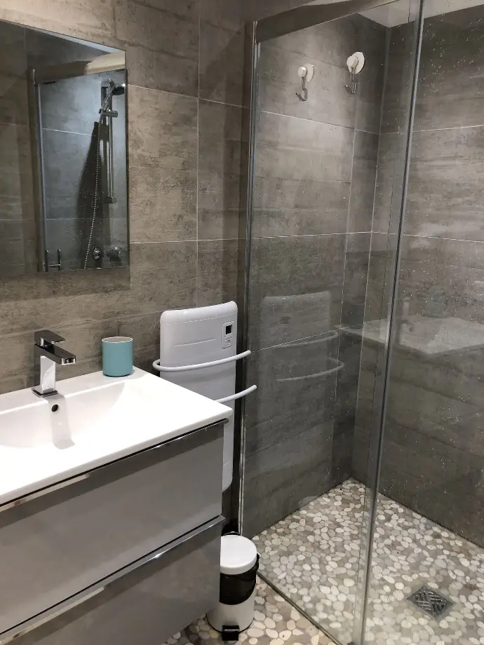 Salle de bain épurée avec cabine de douche en verre, carrelage moderne et sol en galet à Loc'Amargue, Saintes-Maries-de-la-Mer