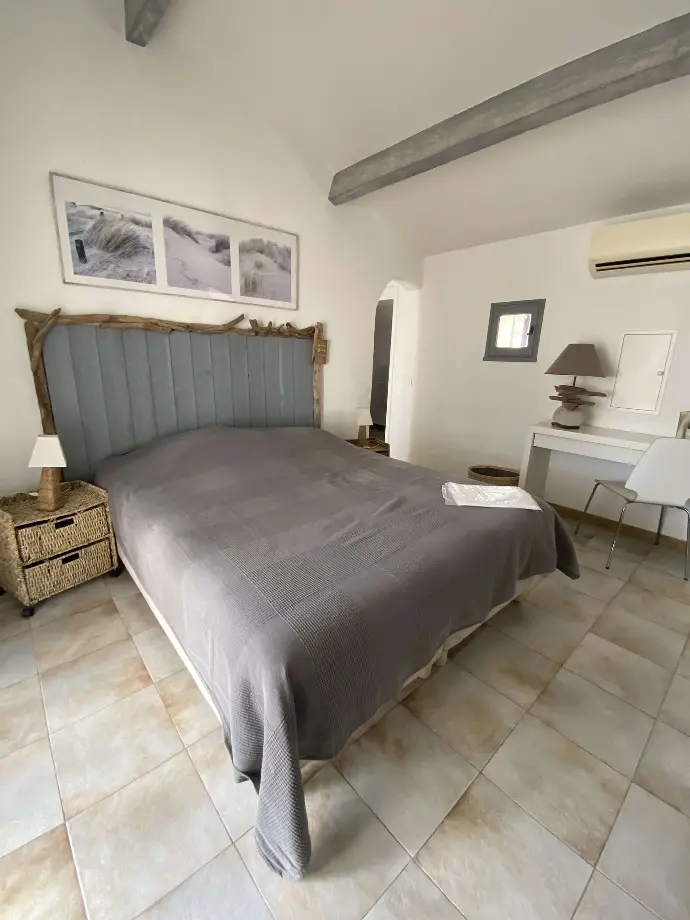 Chambre à coucher élégante avec grand lit, tête de lit rembourrée, et décoration neutre au Mas des Oliviers, Loc'Amargue, Saintes-Maries-de-la-Mer