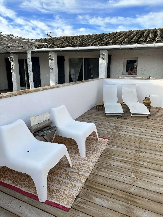 Terrasse avec mobilier de détente blanc, tapis décoratif et vue sur les toits au Mas des Oliviers, Loc'Amargue, Saintes-Maries-de-la-Mer