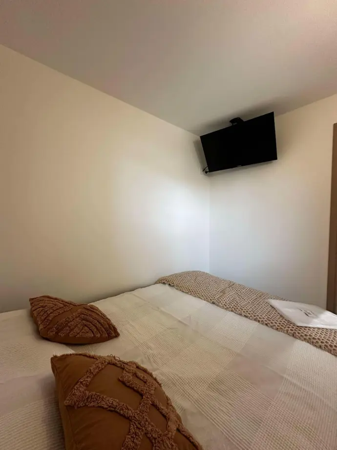 Chambre avec lit double et télévision murale, décorée dans des tons neutres et chaleureux.