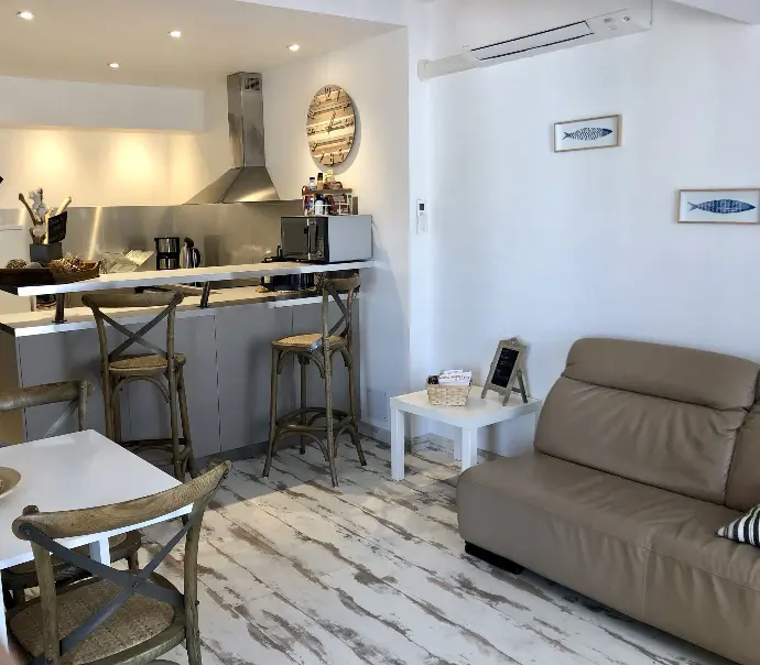 Espace de vie ouvert avec cuisine équipée, îlot central, tabourets de bar et coin salon confortable à Loc'Amargue aux Saintes-Maries-de-la-Mer