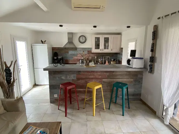 Cuisine vivante et colorée à Loc'Amargue - Un goût des Saintes-Maries-de-la-Mer Cuisine lumineuse avec des tabourets colorés, carrelage au sol et comptoir en bois à Loc'Amargue, Saintes-Maries-de-la-Mer