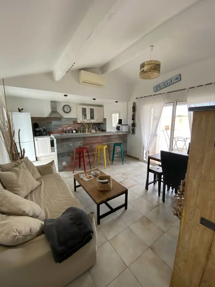Salon spacieux avec cuisine ouverte, tabourets de bar colorés et décoration de plage au Mas des Oliviers, Loc'Amargue, Saintes-Maries-de-la-Mer