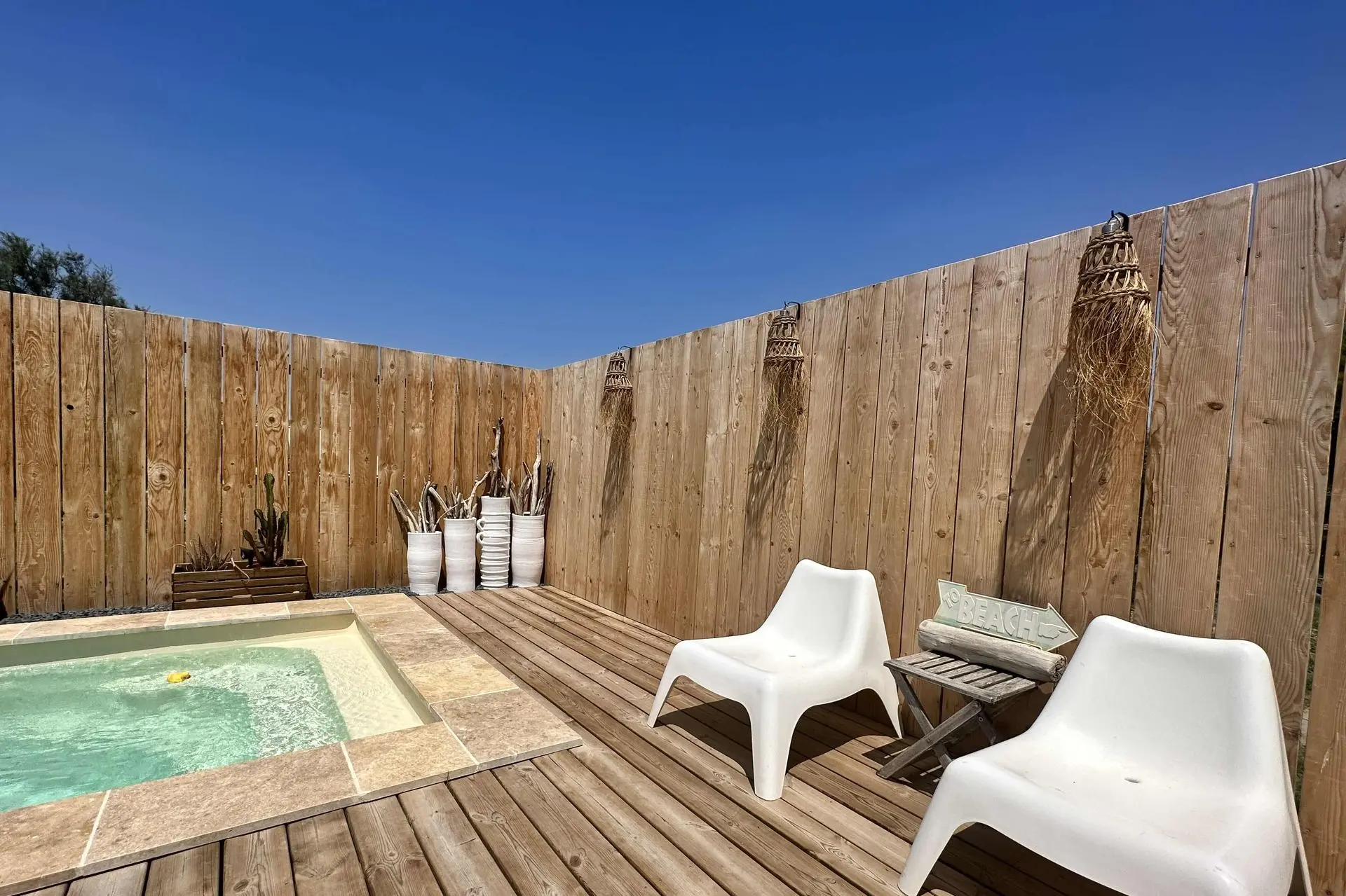 Piscine privée ensoleillée avec chaises blanches et clôture en bois à Loc’Amargue, Saintes-Maries-de-la-Mer